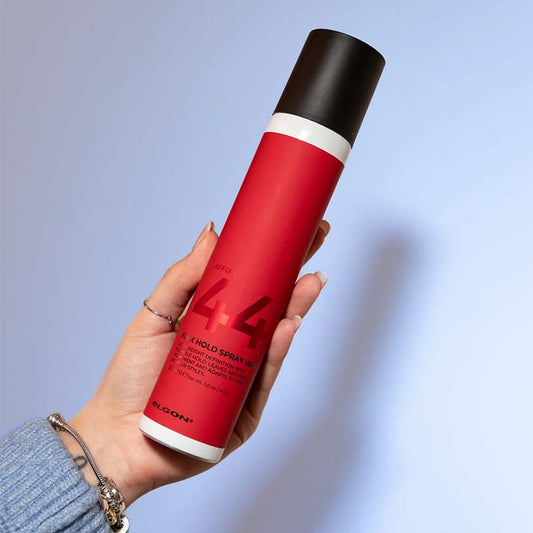 Flacone bianco con etichetta rossa con scritte nere e tappo spray nero.