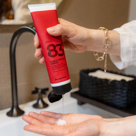 Tubo bianco con sleeve rossa con scritte nere e tappo flip top nero che viene erogato sul palmo di una mano.