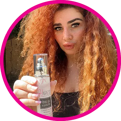 Giovane ragazza dai capelli rossi al fianco dell'olio illuminante Hairesia idralux.